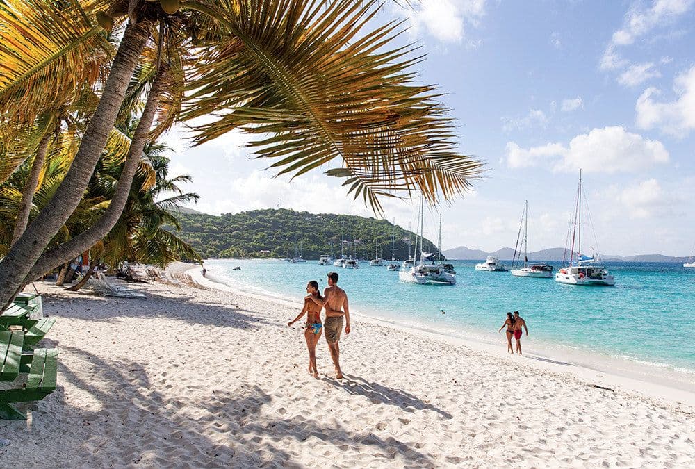 cane garden bay people walking on a beach boats moored