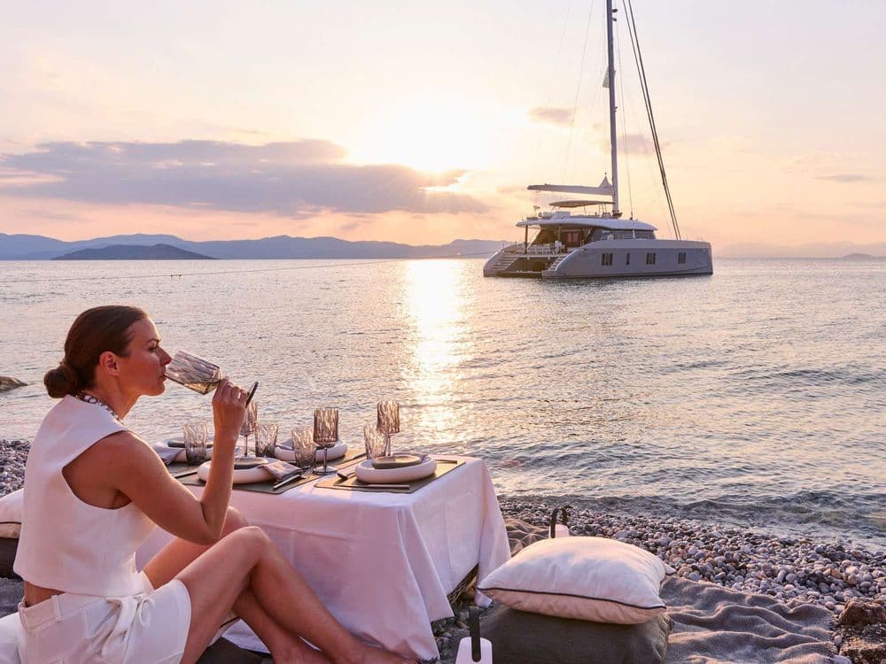 above and beyond crewed greece excursion woman on the beach drinking while sunset