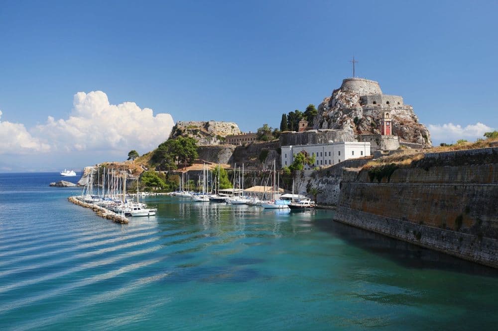 the corfu fortress with boats in a bay